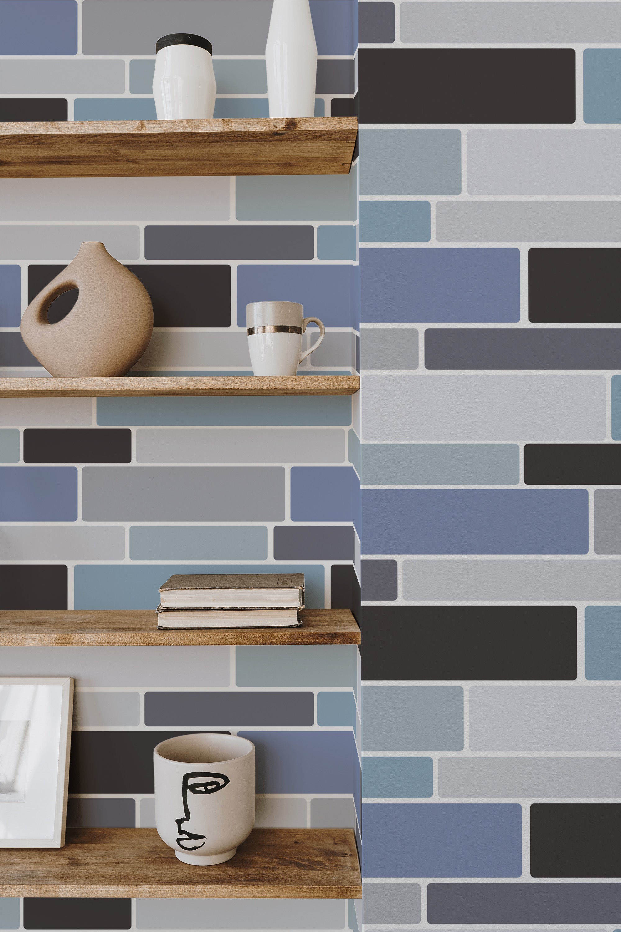 Self-adhesive wallpaper mimicking blue-grey kitchen tiles with floating wooden shelves displaying decorative items.