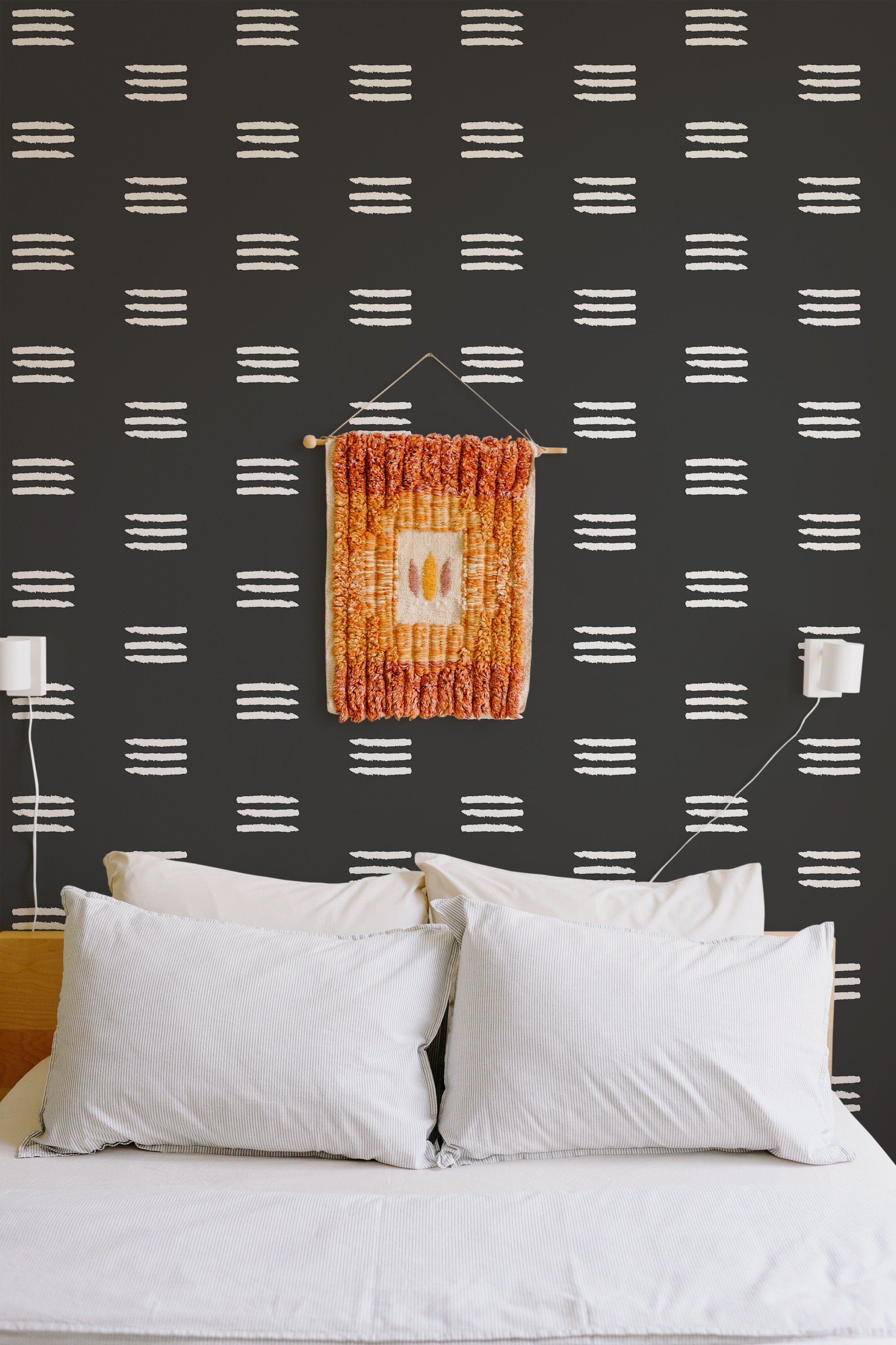 Self-adhesive wallpaper with black background and horizontal white brush stroke stripes in a bedroom setting above a white bed with pillows.
