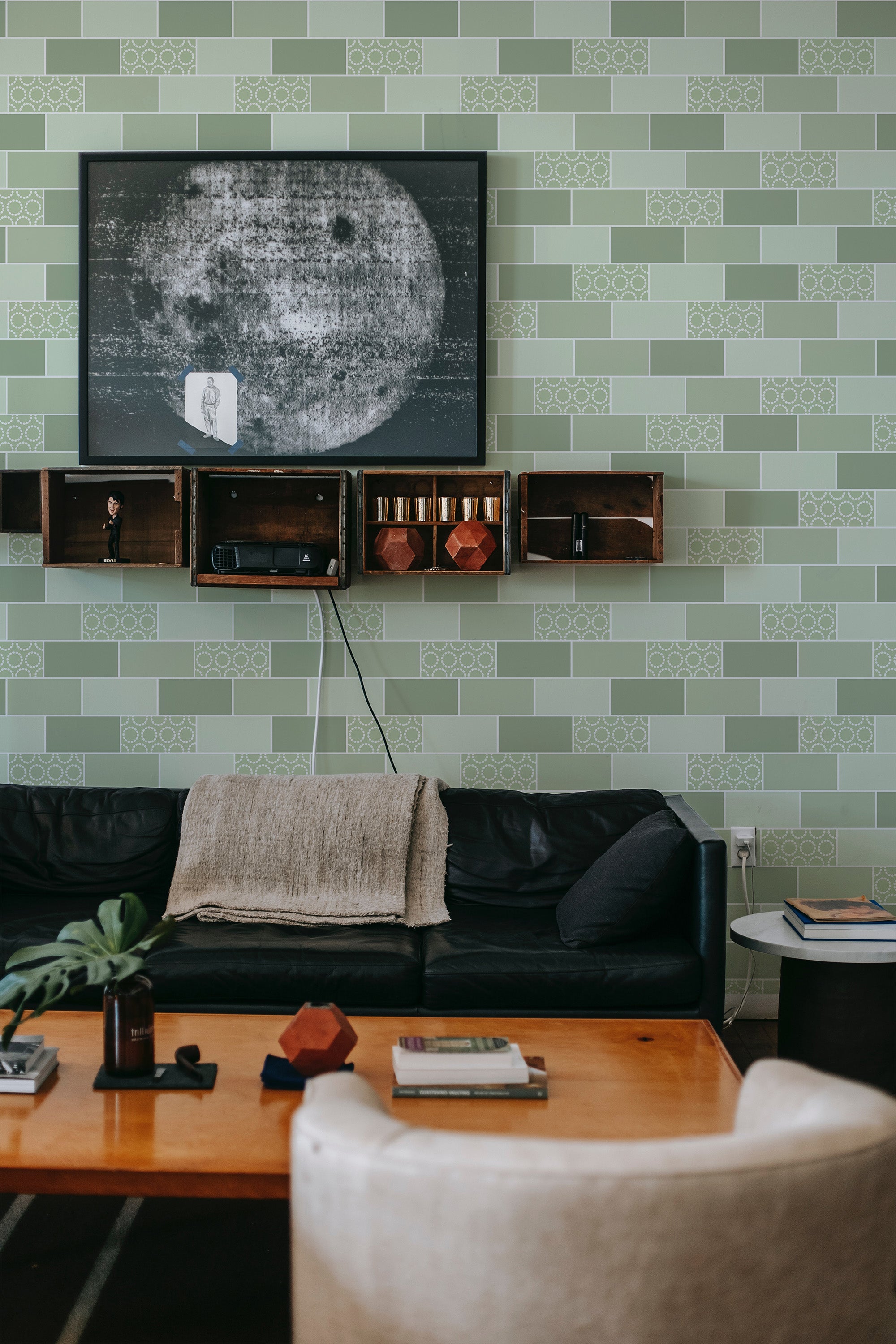A living room with a green tile-designed wallpaper, including a repeating pattern of lighter green squares outlined in white, accented with geometric shapes, giving a contemporary twist to traditional wallpaper.