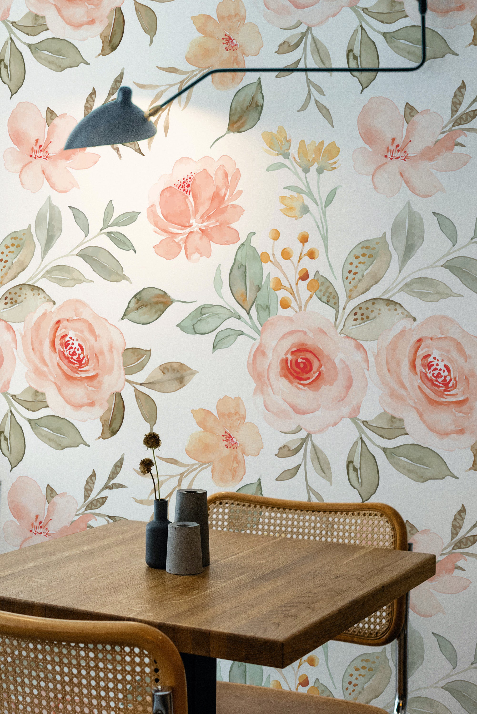 Self-adhesive floral wallpaper with pink rose patterns and green leaves adorning a room's wall, complementing a wooden table and chair set.