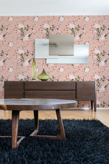 A room with a Spring bird wallpaper on the wall, illustrating a pattern of birds perched on flowering branches against a pink background, traditional wallpaper.