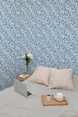 Self-adhesive Tiny blue floral wallpaper with small blue flowers spread evenly on a white background, in a room with a bed and laptop.