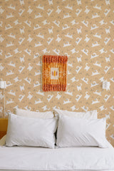 Self-adhesive wallpaper with repeating pattern of playful white cat silhouettes on a beige background, in a cozy room with a bed and white pillows.