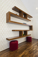 A room with interlocking chain patterned wallpaper in subtle tones, accented by wooden shelves and red stools, traditional wallpaper.