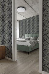 A bedroom with walls covered in dark snake skin patterned traditional wallpaper, complementing the modern decor and green upholstered bed.