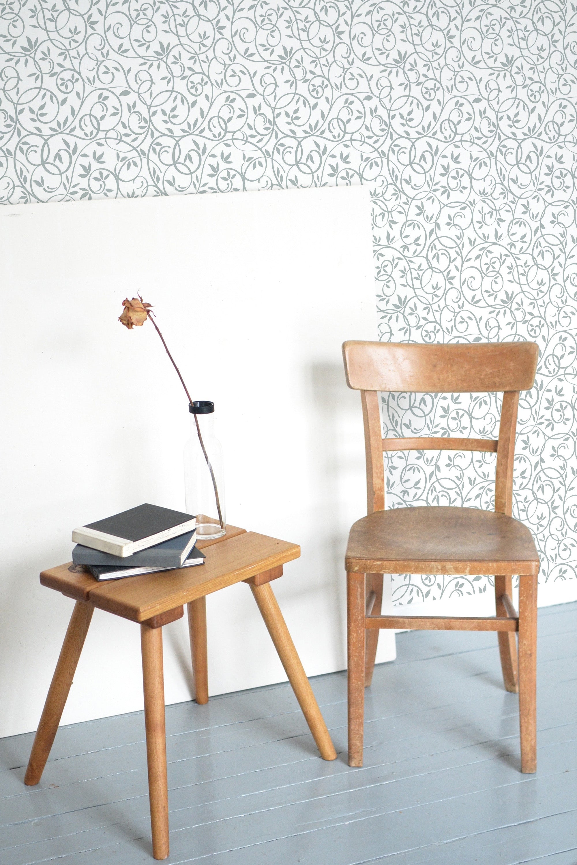 Self-adhesive wallpaper with intricate repeating ornamental pattern, complementing a wooden chair and table set in a room.