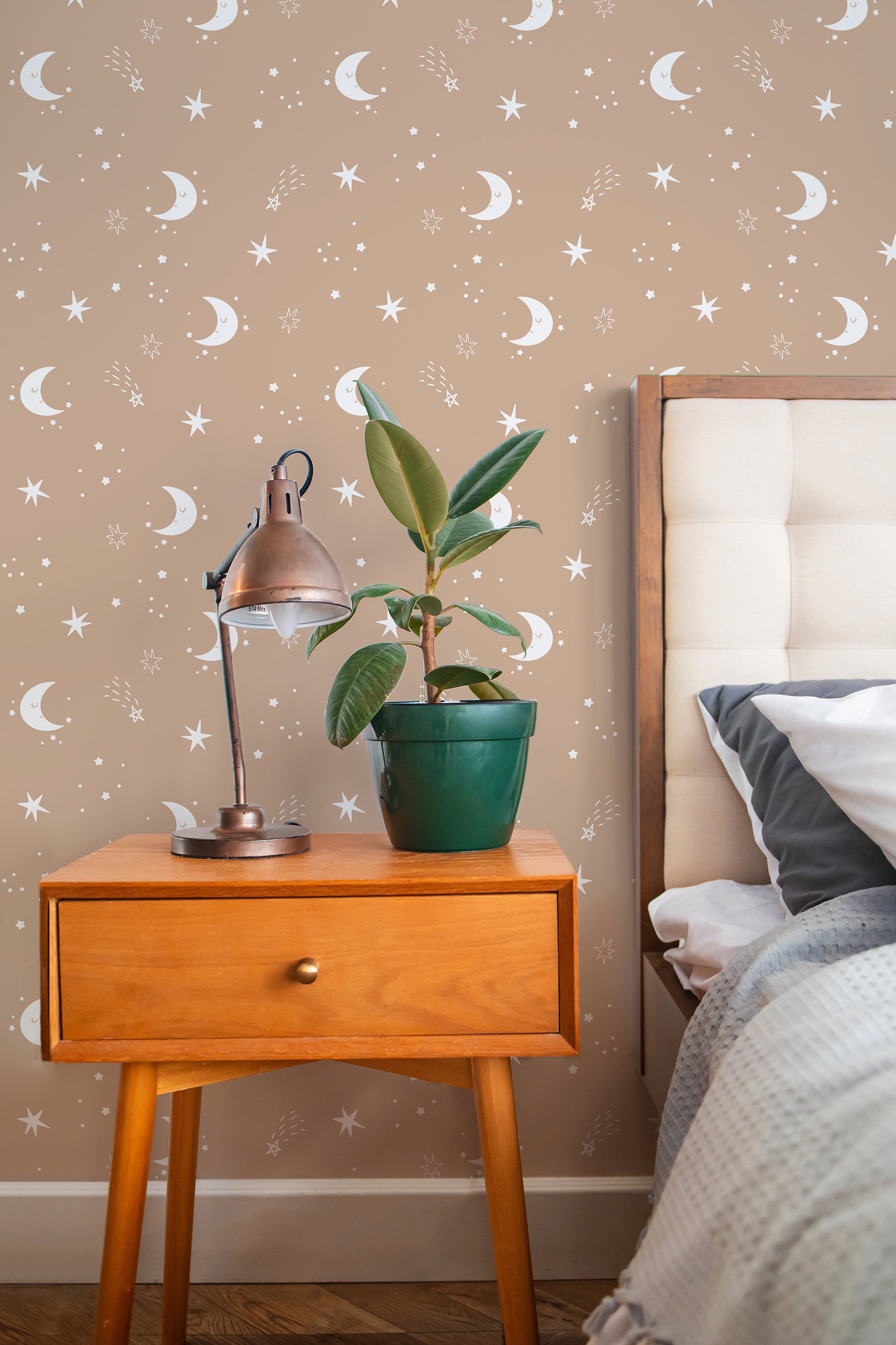 Self-adhesive wallpaper with a celestial pattern of crescent moons and stars on a beige background, decorating a cozy bedroom interior.