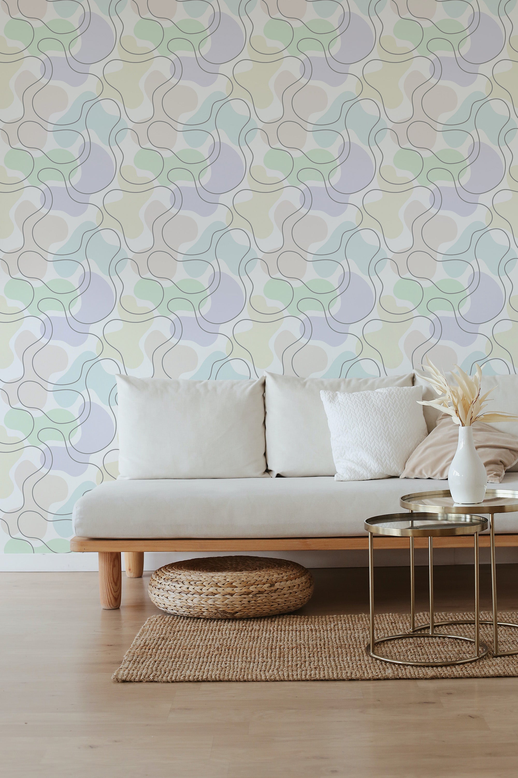 A room with a sofa and table in front of a wall covered in wallpaper with a continuous, interlocking geometric pattern of various pastel colors, creating a modern interpretation of traditional wallpaper.