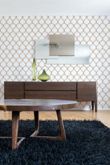 Wall with a repeating pattern of interlocking curved lines in gold against a white background, a mid-century wood sideboard beneath a large modern mirror, and a coffee table on a black rug, traditional wallpaper.
