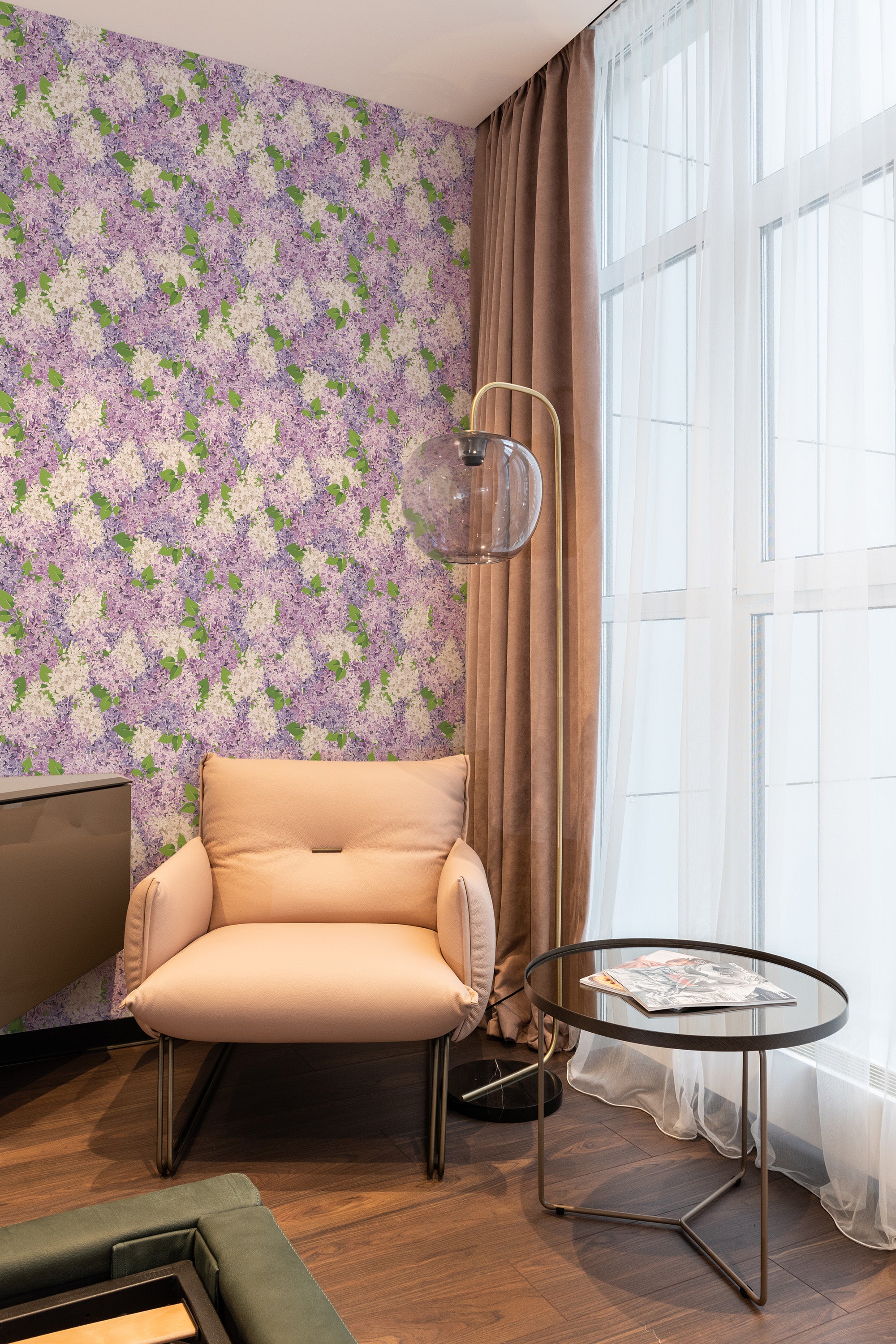 Lilac-themed wallpaper with dense clusters of light purple and white lilac flowers interspersed with green leaves on a soft pastel background. The floral pattern adds a touch of elegance and classic charm to the room, evoking a cozy and inviting atmosphere with its traditional wallpaper.