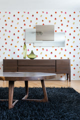 A white wall adorned with a whimsical cupcake pattern in various colors, adding a playful touch to the room. The design incorporates cupcakes of different sizes and colors scattered evenly across the surface, set against a clean white background, creating a fun and lively atmosphere. Furniture and decor in the room, such as a wooden console table and mirrors, complement the design. This is a traditional wallpaper.