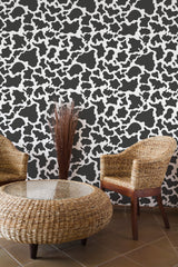 Self-adhesive cow print wallpaper with irregular black and white patches covering the entire wall.