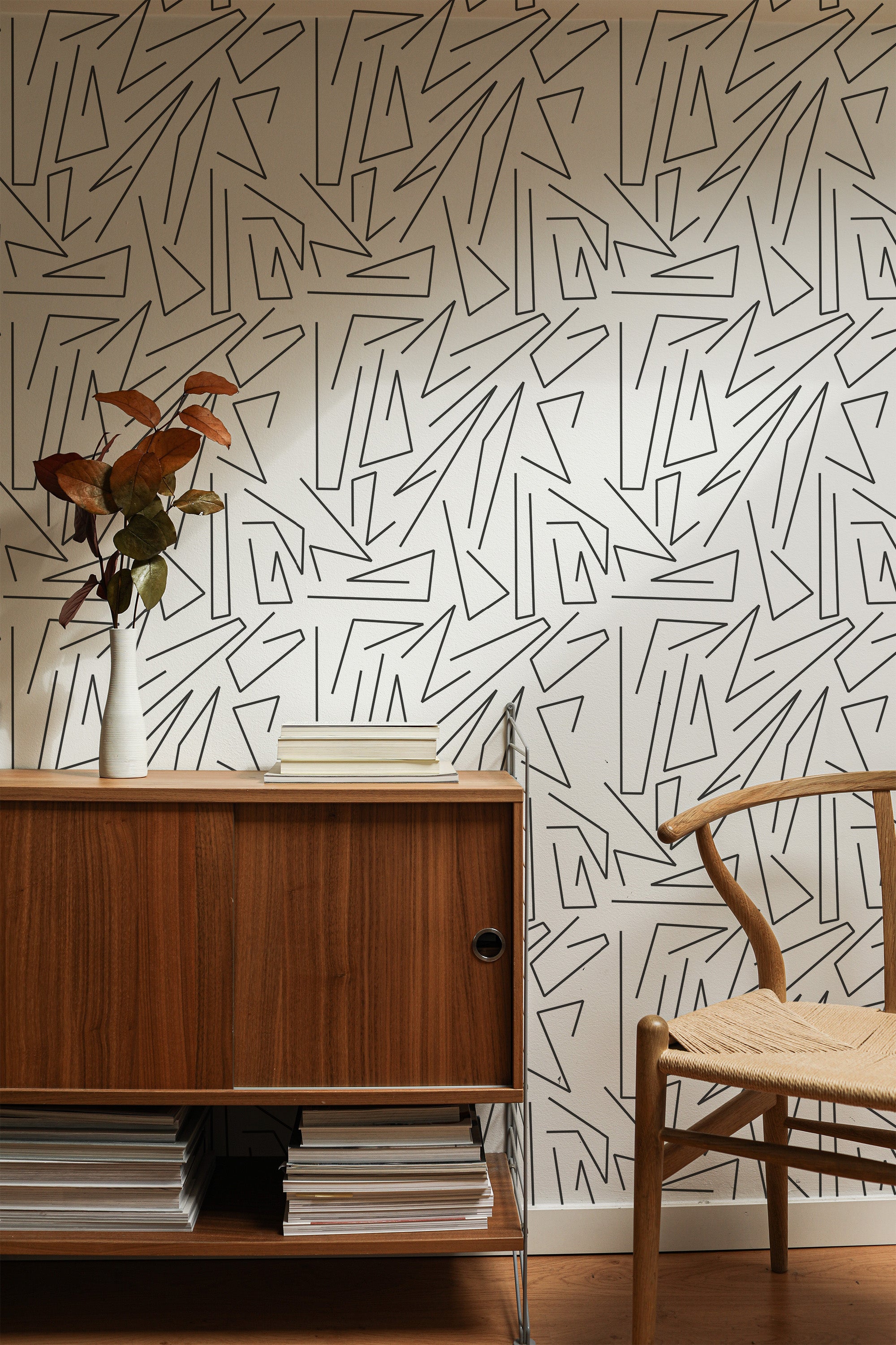 Self-adhesive wallpaper with an abstract line drawing design, characterized by bold, black angular lines on a neutral background, adding a modern and artistic touch to the room.