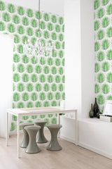 Green palm leaf pattern in a repeating design on white, covering the wall behind a minimalist white table and green stools, adding a fresh, tropical vibe to the room. Traditional wallpaper.