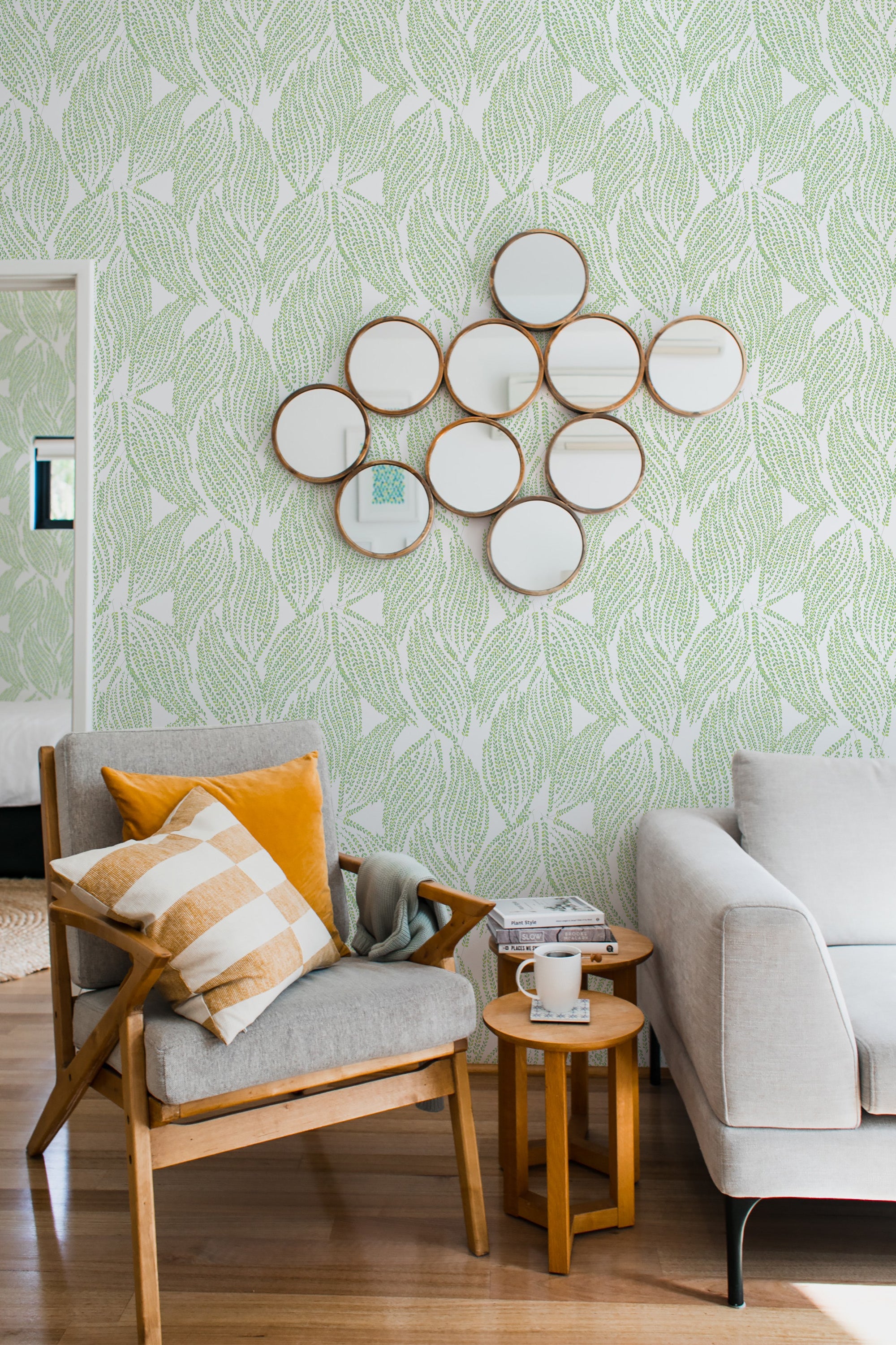 Green leafy pattern covers the walls, gracefully intertwining on a soft white background, creating an organic and fresh ambiance. The repeating leaf motif exudes a sense of nature and elegance, reflecting a classic yet lively aesthetic. Traditional wallpaper.