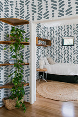 Image shows a room with a wall covered in a Herringbone brush stroke pattern, where bold, dark, brush-like strokes are arranged in a zigzag design across a light background. Traditional wallpaper.