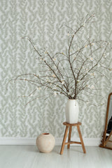 Self-adhesive wallpaper with a delicate pine tree branches design in muted green tones on a soft white background.