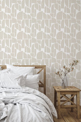 Self-adhesive wallpaper with abstract shapes in neutral tones, enhancing the room's ambiance above a wooden bed and a side table with a simple vase.