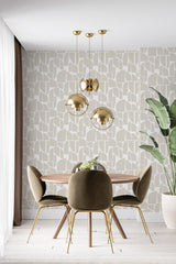 Wallpaper with an abstract shape design in beige and soft cream tones, creating a modern and geometric aesthetic. The room also has elegant pendant lighting, green textured chairs, and a leafy indoor plant, complementing the traditional wallpaper.