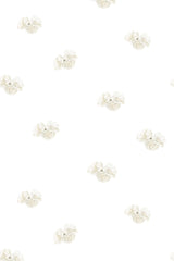White wallpaper with a minimalist design of small, evenly spaced clusters of delicate cream flowers with subtle green leaves on a plain background. Peel and stick removable wallpaper.