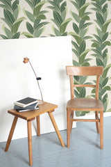 Self-adhesive tropical leaf wallpaper with large, overlapping green leaves against a light beige background, creating a vibrant, lush atmosphere in the room.
