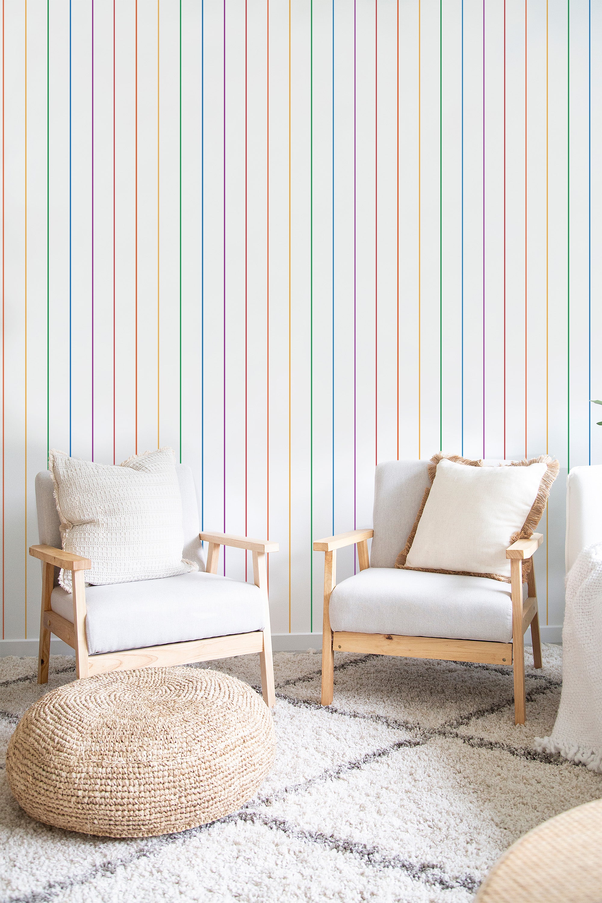 Two armchairs in a cozy room against a wall adorned with vertical rainbow stripes in pastel tones, traditional wallpaper.
