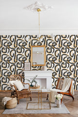 Abstract wallpaper with flowing black, beige, and white brushstrokes creating an intricate pattern, complemented by the neutral tones of the furniture in the room, traditional wallpaper.