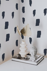 Self-adhesive wallpaper design with navy blue brushstroke patterns scattered on a white background, giving the wall an artistic and modern appearance.