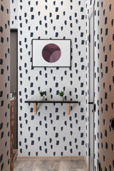 A room with wallpaper designed with irregular black brush strokes scattered on a white background, creating a bold and contemporary pattern that complements the space while mimicking hand-painted art. Traditional wallpaper.