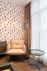 A wall covered in a painted dots print wallpaper with irregular, abstract orange shapes on a white background, creating a modern yet traditional wallpaper.
