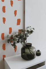 Self-adhesive wallpaper with an abstract painted dots print, featuring bold orange brushstroke-like marks on a white background.