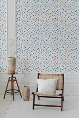 Wallpaper with a design of small, evenly spaced blue dots scattered across a white background, creating a subtle and minimalist pattern of tiny specks. The dots are uniform in size, contributing to a simple and clean aesthetic. The wallpaper contrasts with the neutral tones of the room's furniture, bringing a touch of pattern to the otherwise minimalist space. Traditional wallpaper.