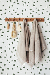 Self-adhesive wallpaper with a Green Dalmatian design, characterized by randomly spaced olive-green spots on a white background.