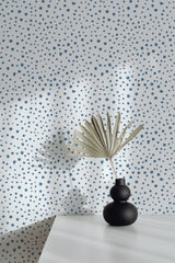 Self-adhesive wallpaper with a speckled dot pattern in scattered blue spots against a white background, adding a playful and modern touch to the room.