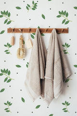 Self-adhesive wallpaper on a wall with a Leaf dots design, combining green leaves and small black dots on a white background for a natural, minimalist look.