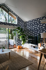 A modern living room with dark wallpaper adorned with a Japanese cloud pattern in white against a charcoal background, complementing the natural light and wooden flooring. Traditional wallpaper.