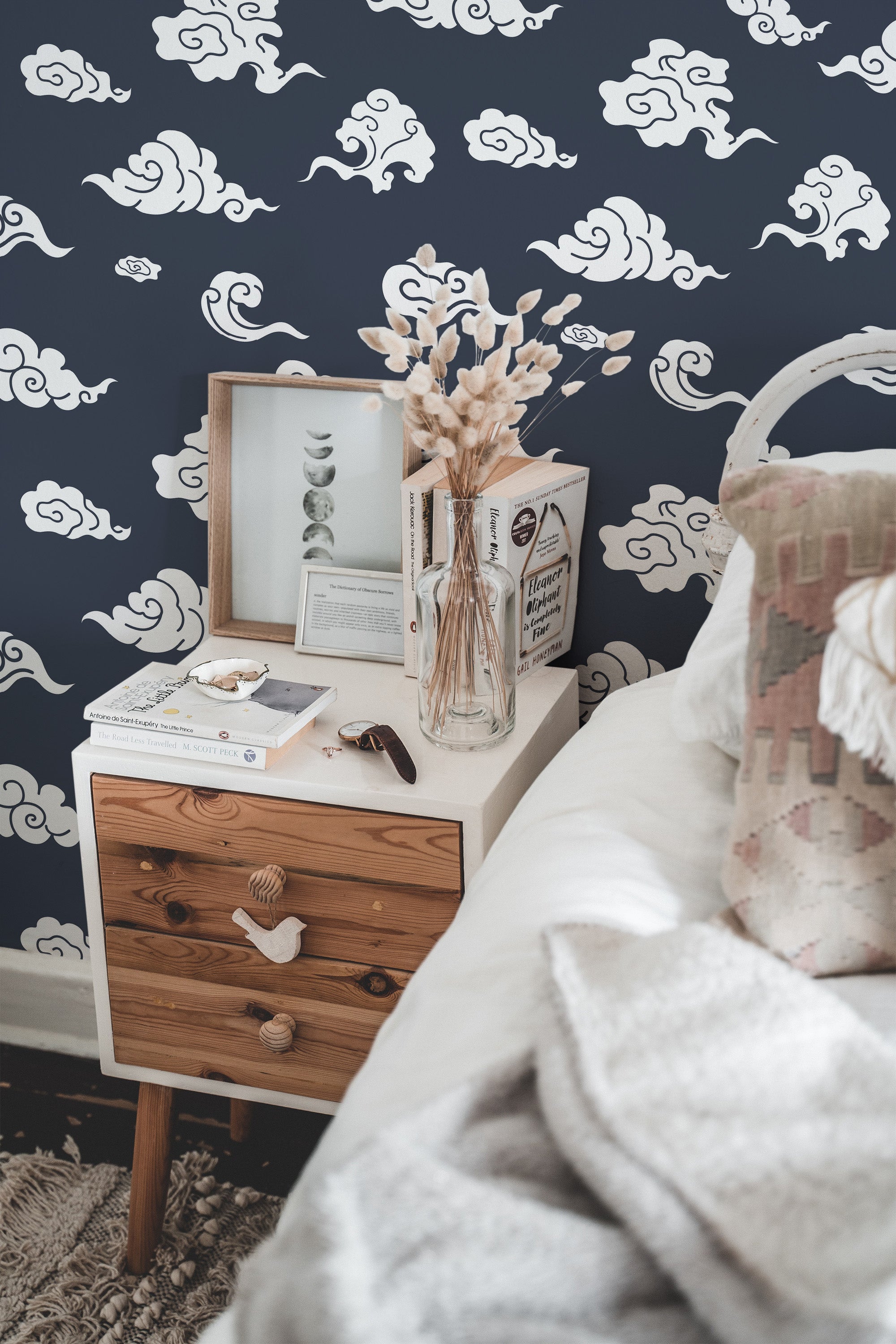 Self-adhesive Japanese cloud wallpaper with white swirling cloud patterns on a deep navy background, creating a calm and elegant atmosphere beside a white bed and wooden nightstand.