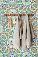 Self-adhesive wallpaper with a Mandala design featuring intricate circular patterns in shades of blue, green, and beige, creating a soothing and symmetrical background for the rustic wooden towel rack and neutral-colored towels hung on the wall.