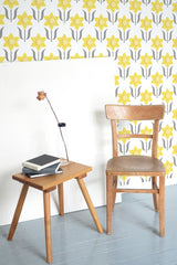 Self-adhesive yellow art nouveau wallpaper with a repeating floral pattern that consists of stylized yellow flowers with green stems on a white background.