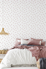 Wallpaper with a vintage rose design, featuring subtle, scattered pink roses on a white background in a bedroom with a soft, muted color palette that complements the traditional wallpaper.