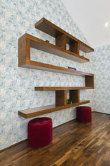 Light blue wallpaper with white blossoms and green leaves on thin branches covering the wall, creating a nature-inspired pattern. Traditional wallpaper.