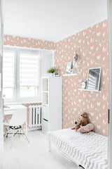 The wallpaper design, called Nursery leaves, has soft pastel tones with a repetitive pattern of stylized leaf shapes in light pink and white, creating a calming and cozy atmosphere. Traditional wallpaper.