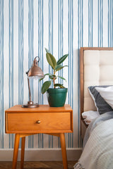 Self-adhesive blue striped wallpaper with vertical irregular lines set against a white background, adding a subtle yet modern texture to the room.