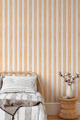 Self-adhesive wallpaper with an aesthetic striped design in warm earthy tones, installed vertically in a cozy room setting.