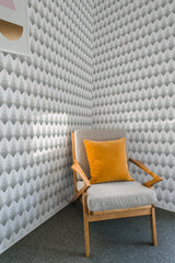 A room with Colorful Art Deco wallpaper featuring a repetitive, geometric pattern in a black and white color scheme. The design has a chevron-like motif with a modern yet vintage feel, complementing the simple furniture in the space. Traditional wallpaper.