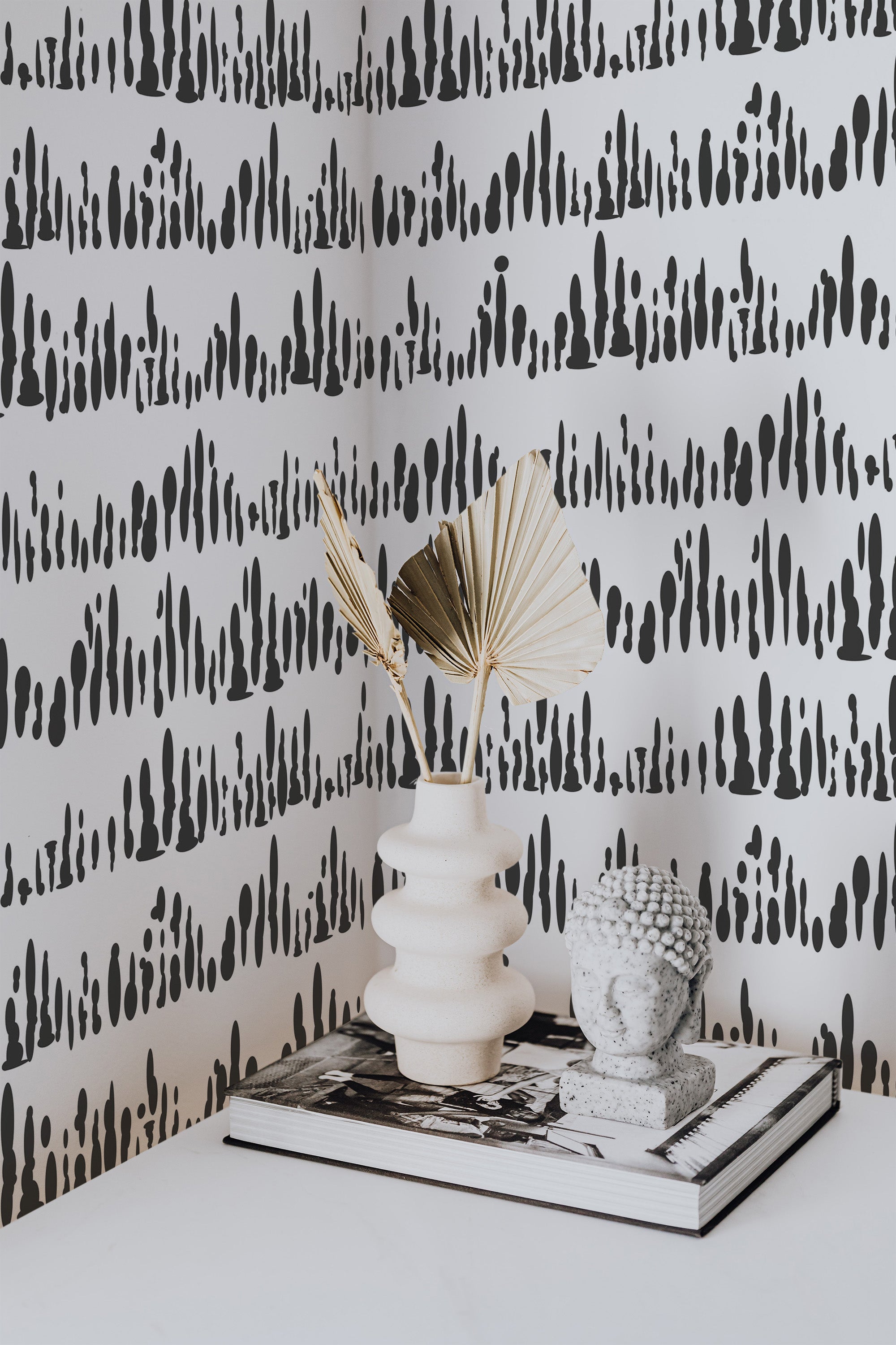 Self-adhesive wallpaper with an abstract Montezuma design of bold black vertical brushstrokes on a white background, creating a striking, modern pattern.