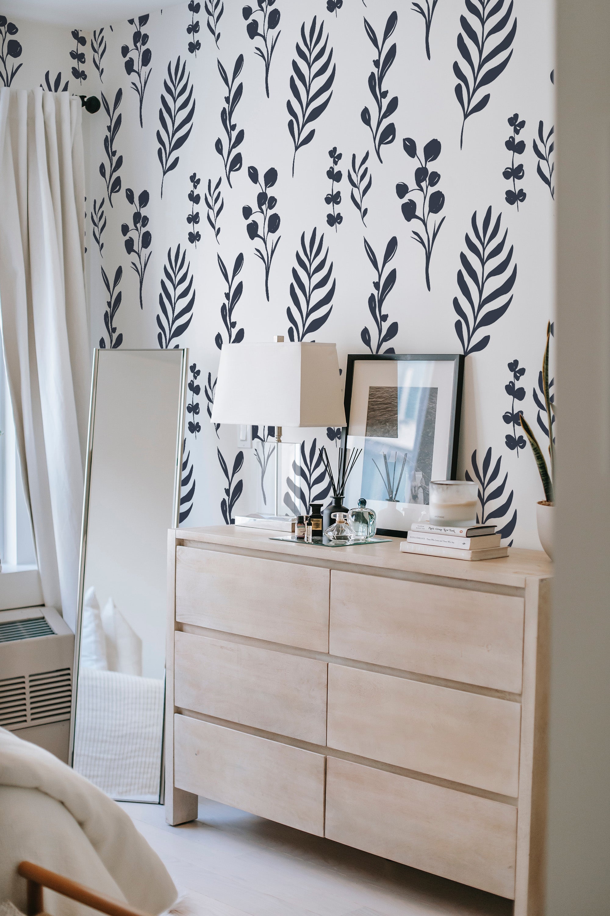 A room with walls covered in traditional wallpaper with a Tropical leaves design, characterized by a pattern of dark leafy branches against a crisp white background.