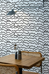 Self-adhesive wallpaper with a modern abstract line art design, showcasing irregular black wavy lines on a white background. The minimalistic and contemporary style adds visual texture to the room.