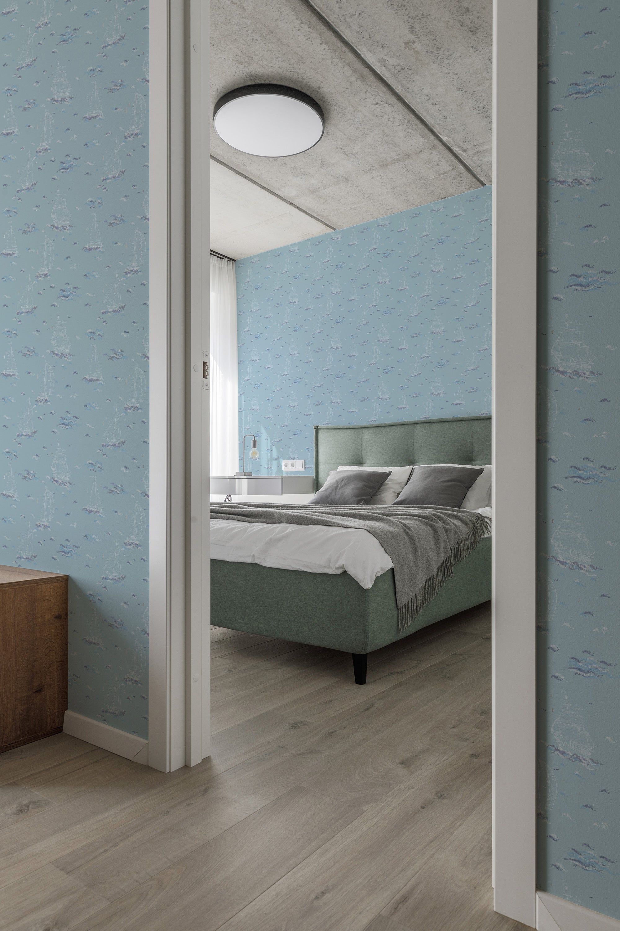 A bedroom with wallpaper showing light blue shades and artistic waves, sailboats, and seagulls scattered throughout the pattern. The restful, nautical motif contributes to a serene atmosphere in the room. Traditional wallpaper.