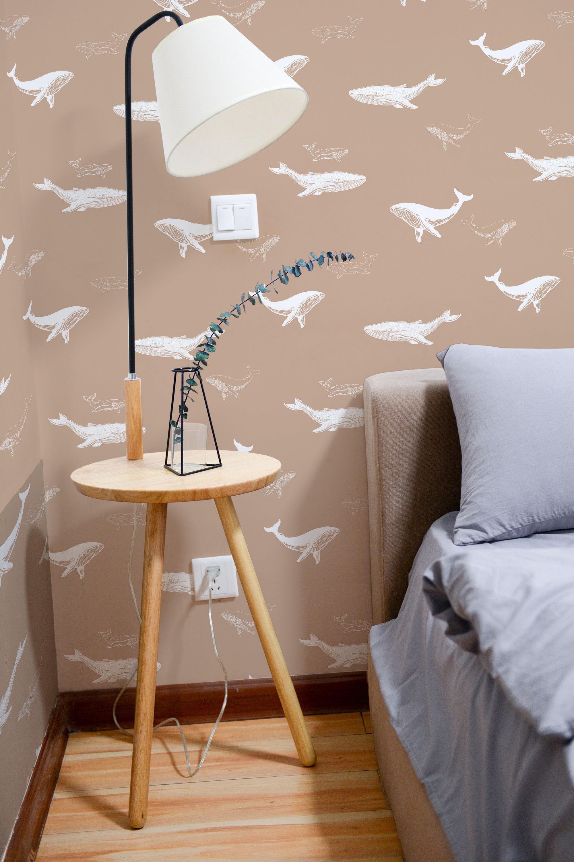 Self-adhesive wallpaper with whimsical white whale illustrations swimming on a soft beige background, adding a playful yet serene touch to the bedroom.
